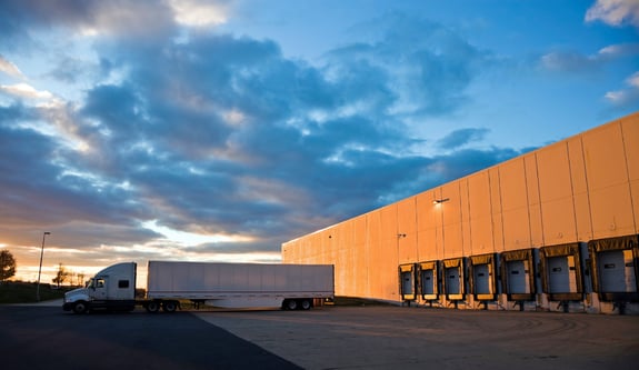 Truck parked outside a warehouse at sunset