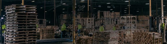 People working inside a warehouse with pallets