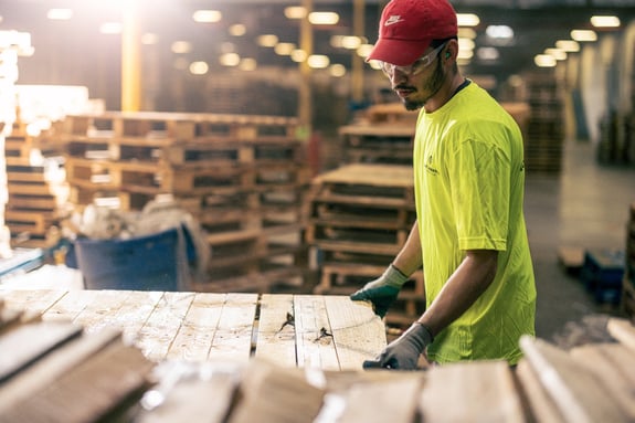 Man in a yellow PLA t-shirt moving a crate