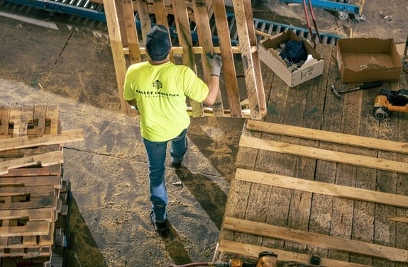 Man in a yellow PLA t-shirt moving a pallet